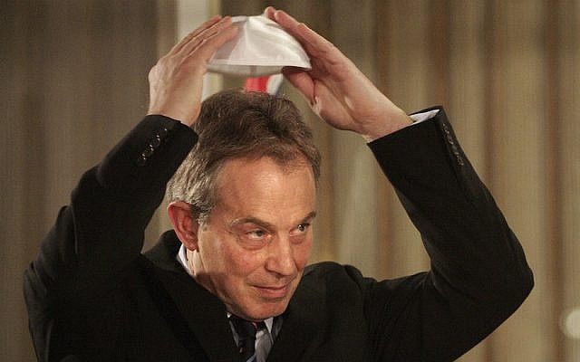 Former British prime minister Tony Blair puts on a kippah for a Hannukah ceremony with then Israeli prime minister Ehud Olmert (unseen) on December 18, 2006 in Jerusalem, Israel. (JTA/Getty Images)