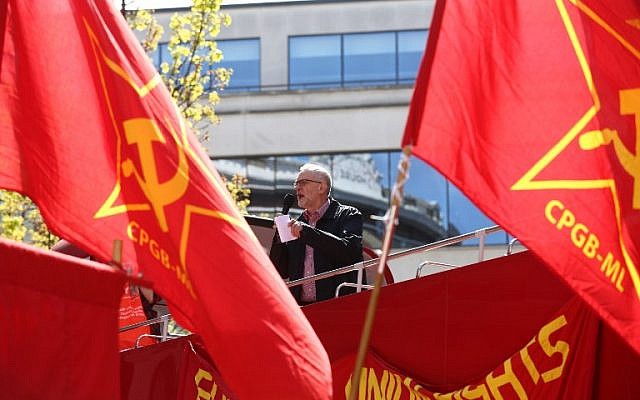 Britain's opposition Labour Party leader Jeremy Corbyn gives a speech from the top of a double-decker bus as Communist Party of Great Britain (Marxist-Leninist) flags fly at a May Day rally in London on May 1, 2016. (AFP / JUSTIN TALLIS)