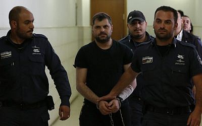 Yosef Haim Ben-David, center, the ringleader in the killing of Palestinian teenager Mohammed Abu Khdeir last year, is escorted by Israeli policemen at the district court in Jerusalem on May 3, 2016.  (AFP/AHMAD GHARABLI)