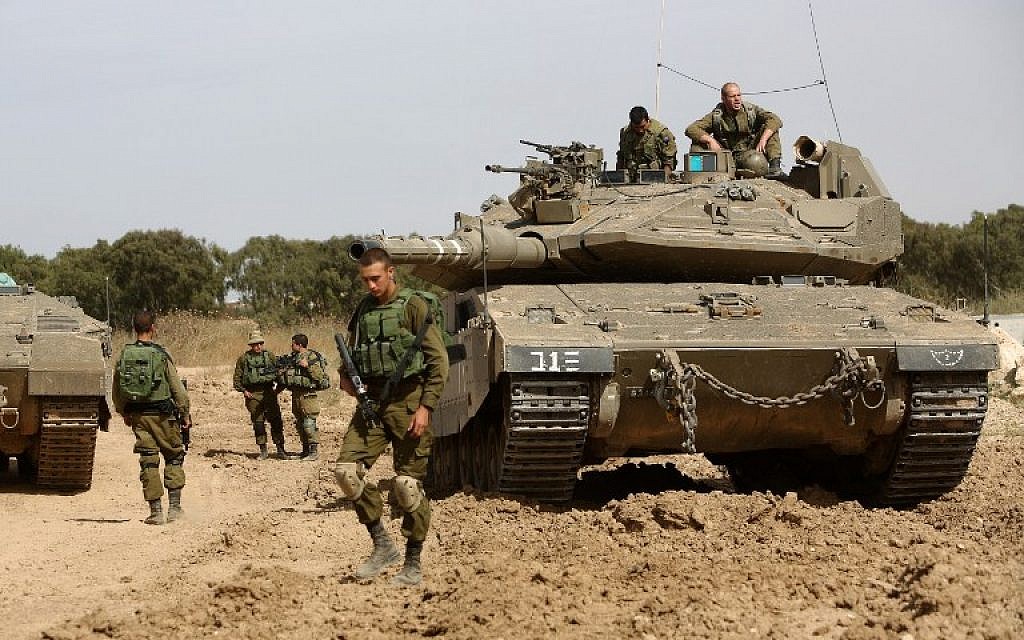 Israeli soldiers stand guard with their tank along the border between Israel and the Gaza Strip near the southern Israeli kibbutz of Nahal Oz on May 4, 2016. (AFP/Menahem Kahana)
