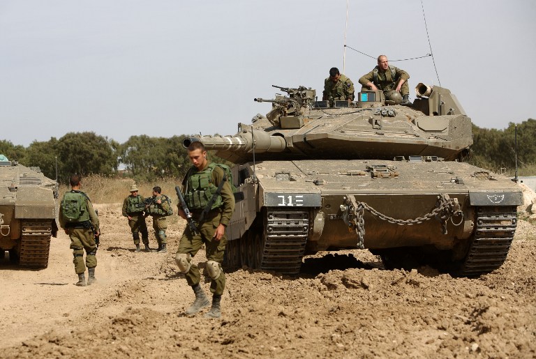 Israeli soldiers stand guard with their tank along the border between Israel and the Gaza Strip near the southern Israeli kibbutz of Nahal Oz on May 4, 2016. (AFP/Menahem Kahana)
