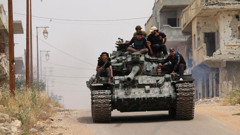 Opposition fighters drive a tank in a rebel-held area of the southern Syrian city of Daraa, during renewed clashes with regime loyalists on May 10, 2016. (AFP Photo/Mohamad Abazeed)