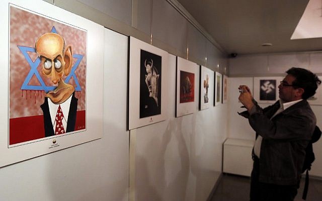 An Iranian man takes a photo of an anti-Israel cartoon displayed at the second international exhibition of drawing and cartoons on the Holocaust in Tehran on May 14, 2016. (AFP PHOTO / ATTA KENARE)