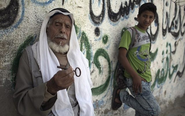 Palestinian refugee Ibrahim Abu Mustaf, 83, who says is a former inhabitant of the town of Beersheva, carries the key to his former home as he sits next to a child outside his home in the Khan Yunis refugee camp in the southern Gaza Strip on May 15, 2016. (AFP PHOTO / SAID KHATIB)