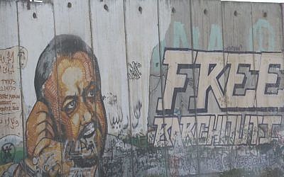 An image of Marwan Barghouti is seen painted on the security fence near the West Bank village of Qalandiya on May 6, 2016. (Photo by Haytham Shtayeh/Flash90)