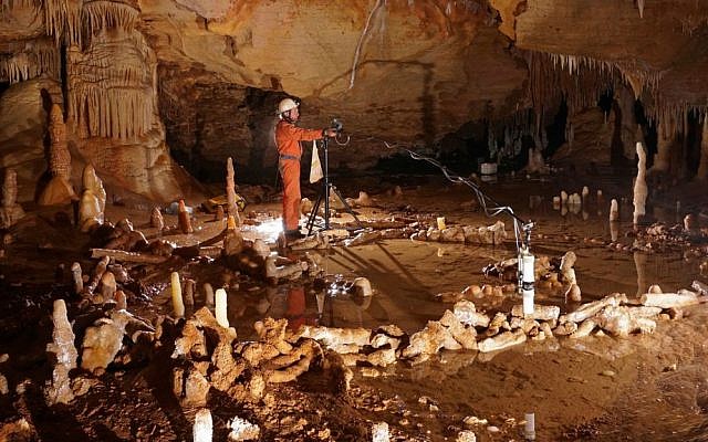 In this undated image released by CNRS on Wednesday May 25, 2016, a scientist takes measurements of stone rings forged by Neanderthals inside a cave on Bruniquel in France. (Etienne Fabre/CNRS via AP)