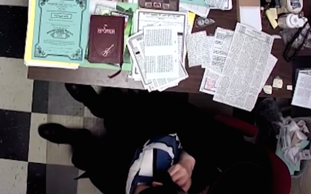 A screenshot from an 11-minute video showing a Hasidic principal handling a young boy. (Screenshot from YouTube)