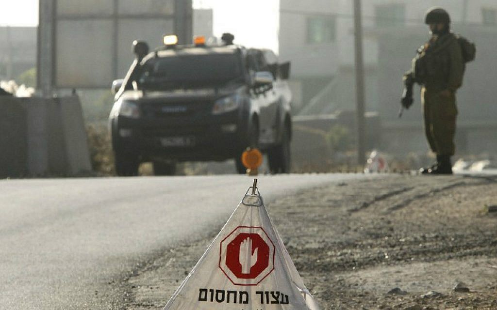 IDF soldiers man a temporary checkpoint at the entrance to the Palestinian village of Yatta in the southern West Bank on June 9, 2016 after the army entered the village in search of clues related to a shooting attack the previous night in Tel Aviv in which four people were killed and 16 others wounded. (Hazem Bader/AFP)