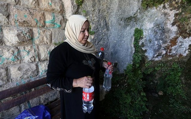 A member of the Salim family carries bottles filled with spring water on June 23, 2016 in Salfit, north of Ramallah (AFP PHOTO / JAAFAR ASHTIYEH)