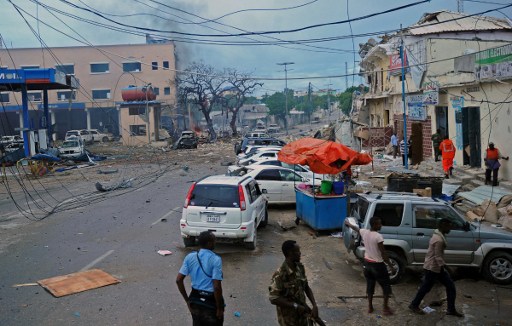 People and Somali security forces walk across the scene of a car bomb attack claimed by Al-Qaeda-affiliated Shabab militants which killed at least 5 people, on the Naasa Hablood hotel in Mogadishu on June 25, 2016. (AFP PHOTO / MOHAMED ABDIWAHAB)