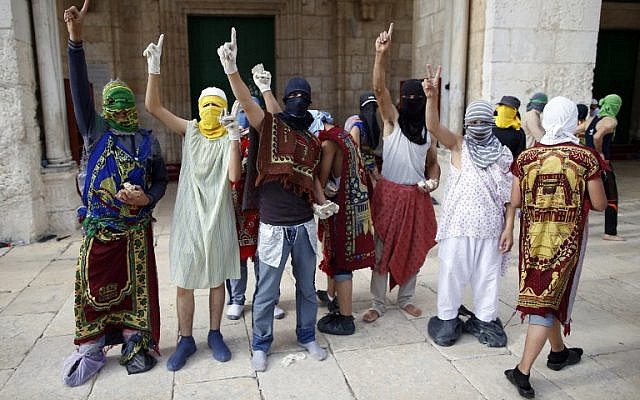 Masked Palestinian protesters wearing pieces of cloth around their bodies gesture during clashes with the Israeli police at Jerusalem's Temple Mount compound for the thrid consecutive day on June 28, 2016. (AFP/AHMAD GHARABLI)