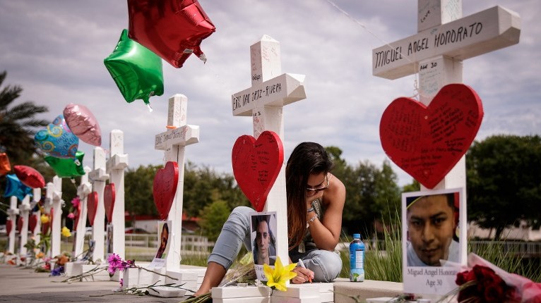 A woman writes a note on a cross at a memorial for each of the 49 victims of the Pulse Nightclub, next to the Orlando Regional Medical Center, June 17, 2016 in Orlando, Florida (Drew Angerer/Getty Images/AFP)