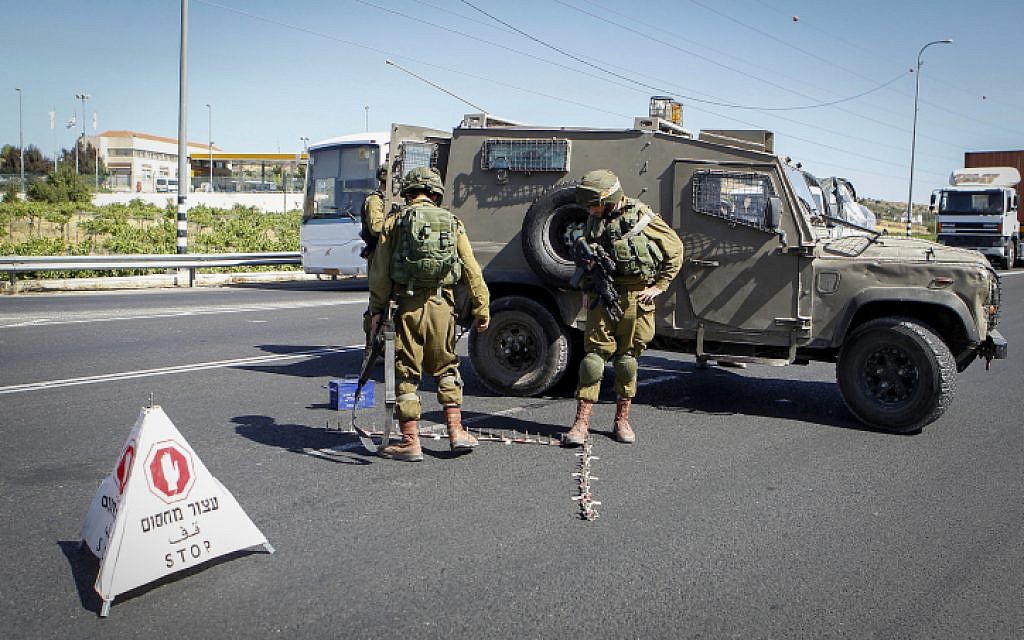 Israeli soldiers set up a checkpoint at the entrance to the Kiryat Arba settlement in the West Bank on June 30, 2016, after a Palestinian teenager stabbed and killed a 13-year-old Israeli girl there. (Wisam Hashlamoun/Flash90)