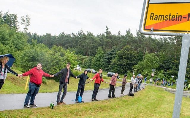Peace activists form a human chain on the street leading towards the US air base during the 'Stopp-Ramstein' campaign in Ramstein, Germany, Saturday June 11, 2016 (Oliver Dietze/dpa via AP)