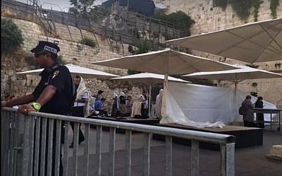 A police officer stands in front of a makeshift partition erected ahead of an Orthodox prayer service at the mixed gender Western Wall plaza on June 14, 2016. screen capture: Facebook) 