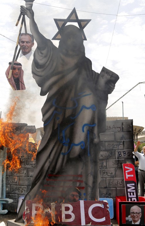 A statute depicting the Statue of Liberty decorated with a Star of David on its head and holding portraits of former British prime minister Tony Blair and Saudi Foreign Minister Adel al-Jubeir is set ablaze by Iranian protesters during a parade marking al-Quds (Jerusalem) Day in Tehran on July 01, 2016. (AFP photo) Tens of thousands joined pro-Palestinian rallies in Tehran, as the annual Quds Day protests take on broader meaning for a region mired in bitter disputes and war. On the bottom R a portrait of Australian born media magnate Rupert Murdoch. / AFP PHOTO / ATTA KENARE