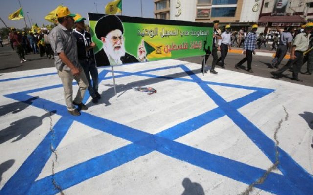 Illustrative: Iraqi men stand on an Israeli flag and hold a banner depicting Iran's Supreme Leader Ayatollah Ali Khamenei as they take part in a parade marking al-Quds (Jerusalem) Day in Baghdad, July 1, 2016. (AFP Photo/Ahmad Al-Rubaye)