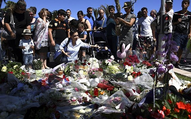 People lay flowers in the street of Nice to pay tribute to the victims the day after a gunman smashed a truck into a crowd of revellers celebrating Bastille Day, killing at least 84 people, on July 15, 2016. (AFP Photo/Anne-Christine Poujoulat)