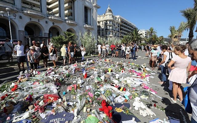 People gather near flowers placed at a makeshift memorial near the Promenade des Anglais in Nice on July 17, 2016, in tribute to the victims of the Bastille Day attack that left 84 dead.(AFP PHOTO / Valery HACHE)