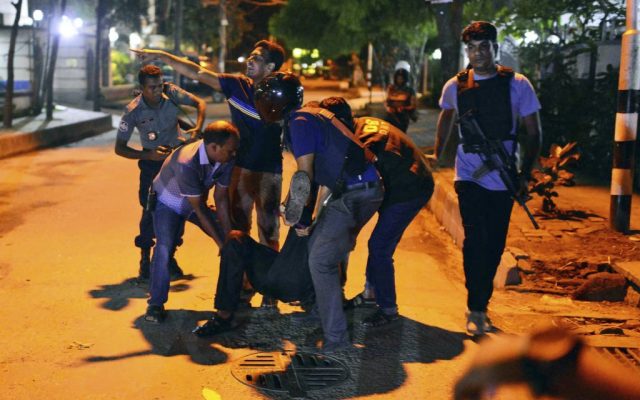 People help an unidentified injured person after a group of gunmen attacked a restaurant popular with foreigners in a diplomatic zone of the Bangladeshi capital Dhaka, Bangladesh, Friday, July 1, 2016. (AP)
