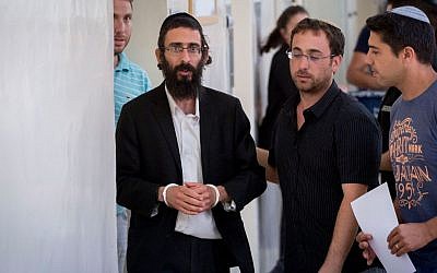 Michael Schlissel, brother of Yishai Schlissel, is led out of the courtroom of the Jerusalem Magistrates Court on July 20, 2016. (Yonatan Sindel/Flash90)