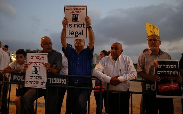 Arab-Israeli Knesset member,Ahmad Tibi (C) holds a poster against administrative detention during a demonstration in support of Palestinian prisoner Bilal Kayed (portrait), who has been fasting for 53 days over his detention without trial, as they demonstrate outside the Ashkelon hospital where he is being held on August 9, 2016. (AFP PHOTO / AHMAD GHARABLI)
