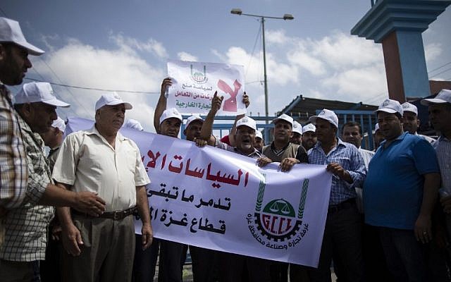 Palestinian businessmen and traders hold banners and shout slogans during a demonstration to protest after Israel suspended their permits to cross to Israel on August 15, 2016 in Beit Hanun, near the Erez crossing point with Israel, in the northern Gaza Strip. / AFP PHOTO / MAHMUD HAMS