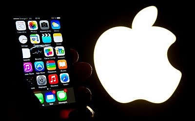 Illustrative. A hand holds an iPhone next to the Apple logo (AFP PHOTO / Philippe HUGUEN)