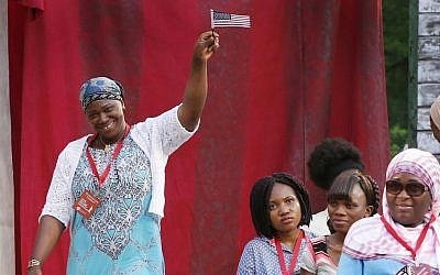 Hatoumata Tounkara, of Mali, waves a miniature US flag, during her naturalization ceremony with 18 other new US citizens sponsored by the International Rescue Committee, the Department of Homeland Security and the Public Theater commemorating World Refugee Day at the Delacorte Theater in New York's Central Park, June 20, 2016. (AP Photo/Kathy Willens)