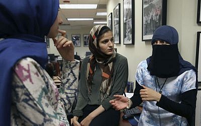 Siham Naser, left, and Lana Kashkeesh, center, both interns at CAIR-Chicago, listen to Itemid Al-Matar, at a news conference, Thursday, Aug. 11, 2016 in Chicago. (Abel Uribe/Chicago Tribune via AP)