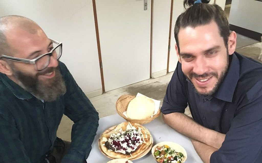 Jalil Dabit, left, an Arab Christian from Ramle, and Oz Ben David, who grew up Jewish in Beersheba, the owners of the Kanaan hummus restaurant in Berlin, smile in an undated photograph. (Toby Axelrod/JTA)