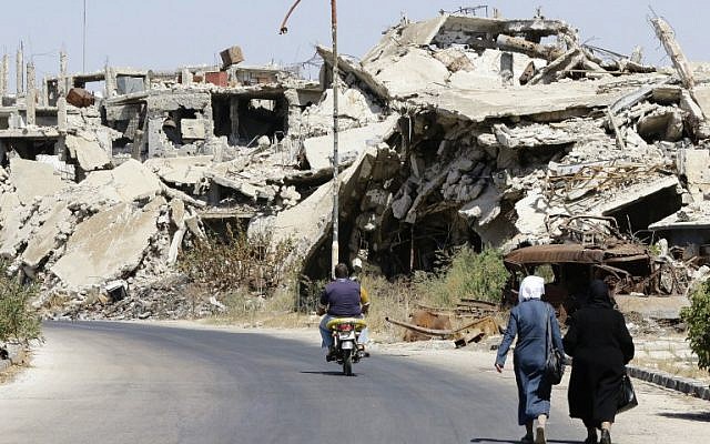 Syrians walk and drive past destroyed buildings in the government held Jouret al-Shiah neighbourhood of the central Syrian city of Homs on September 19, 2016. (AFP PHOTO/LOUAI BESHARA)