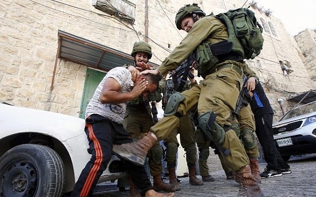 An Israeli soldier kicks a Palestinian man as troops try to arrest him in the flashpoint city of Hebron, in the West Bank, on September 20,2016. (AFP Photo/Hazem Bader)