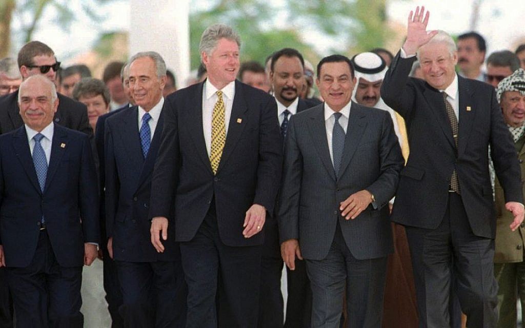 In this March 13, 1996 file photo, Russian President Boris Yeltsin waves as he and (from left to right) Jordan's King Hussein, Israeli Prime Minister Shimon Peres, US President Bill Clinton, Egyptian President Hosni Mubarak and, far right, PLO Leader Yasser Arafat make their way up to pose for the group photo at the end of their one-day Summit for Peacemakers in Sharm el Sheikh, Egypt. (AP Photo/Jerome Delay, File)