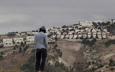 In this Dec. 5, 2012 file photo, a Jewish settler looks at the West Bank settlement of Maaleh Adumim, from the E-1 area on the eastern outskirts of Jerusalem. (AP Photo/Sebastian Scheiner, File)