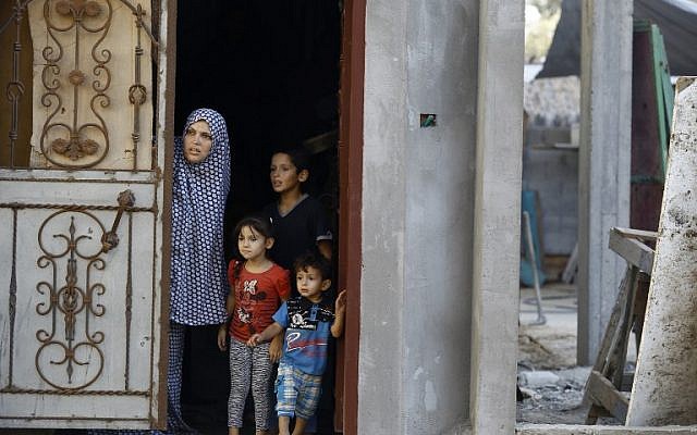 A Palestinian family look out from the doorway of their home in Gaza City's eastern Shujaiya neighborhood following an Israeli military strike on October 5, 2016. (AFP/MOHAMMED ABED)
