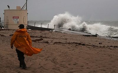 A police officer walks along the beach as waves crash ashore as Hurricane Matthew approaches the area on October 6, 2016 in Singer Island, Florida. (Joe Raedle/Getty Images/AFP)