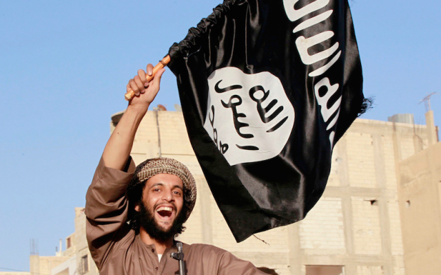 Illustrative: An Islamic State terrorist waves the jihadist organization's flag (CC BY-SA Alatele fr, Flickr)