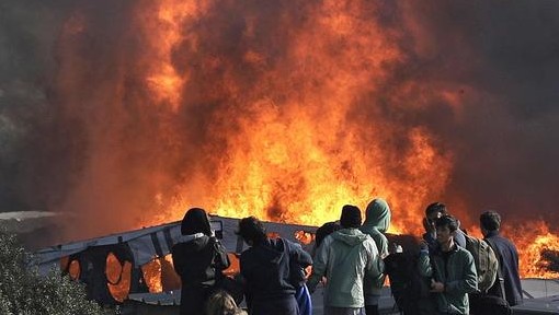 Thick smoke and flames rise from amidst the tents after fires were started in the makeshift migrant camp known as "the jungle" near Calais, northern France, Wednesday, October 26, 2016. Firefighters have doused several dozen fires set by migrants as they left the makeshift camp where they have been living near the northern French city of Calais. (AP Photo/Emilio Morenatti)