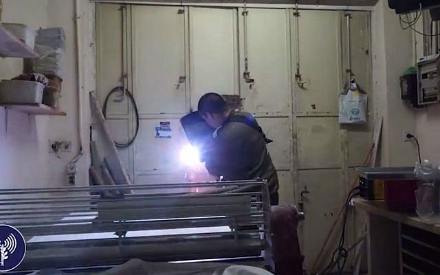 An IDF engineer welds shut the entrance of a candy store belonging to the family of a terrorist who killed two Israelis in a shooting spree in Jerusalem earlier in the week, in the village of a-Ram, north of Jerusalem, October 11, 2016. (screen capture of IDF Spokesperson's Unit footage)