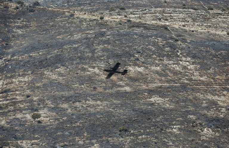 The shadow of a Turkish firefighter jet is seen as it flies over the village of Nataf close to Jerusalem, to help extinguish the ongoing fire in the area, on November 26, 2016. (AFP PHOTO/AHMAD GHARABLI)