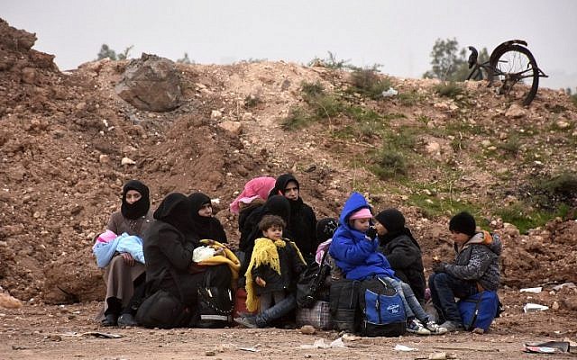 Syrian residents fleeing the eastern part of Aleppo sit on the side of the road after arriving at the Jabal Badro crossing point, which was recently retaken from rebel fighters by the regime forces, on November 30, 2016. (AFP PHOTO/George OURFALIAN)
