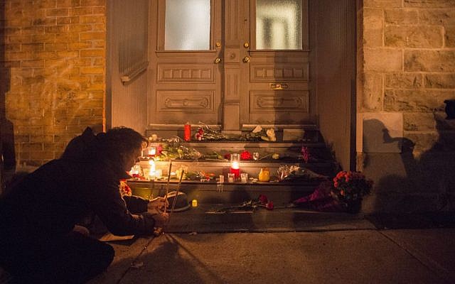 A man places candles in front of the home of singer and poet Leonard Cohen, Thursday, Nov. 10, 2016 in Montreal. (Paul Chiasson/The Canadian Press via AP)