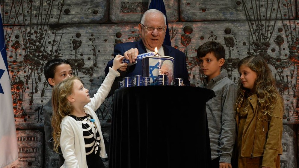 President Reuven Rivlin lights candles with children at a commemoration ceremony for murdered Prime Minister Yitzhak Rabin at the Presidential Residence in Jerusalem on November 10, 2016. (Chaim Zach/GPO)