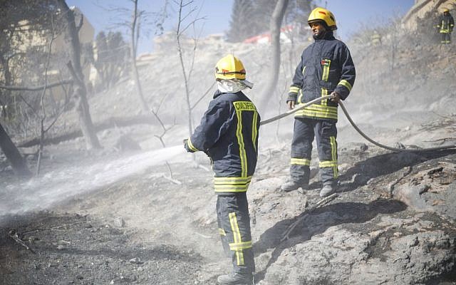Palestinian firefighters work in Haifa, Israel, Friday, Nov. 25, 2016. Firefighters have reined in a blaze that spread across Israel's third-largest city of Haifa and forced tens of thousands of people to flee their homes. (AP Photo/Ariel Schalit)