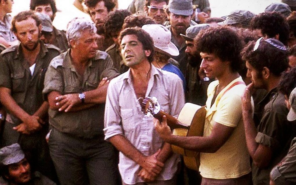 Leonard Cohen, center, performing with Israeli singer Matti Caspi, on guitar, for Ariel Sharon, with arms crossed, and other Israeli troops in the Sinai in 1973. (Courtesy of Maariv via JTA)