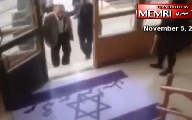 An Iranian professor avoids stepping on an Israeli flag painted onto the ground at a university in northeastern Iran, in footage released November 5, 2016. (MEMRI/screenshot)