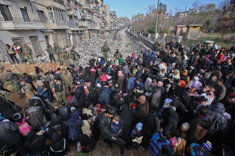 Syrian residents fleeing the violence gather at a checkpoint, manned by pro-government forces, in the Maysaloun neighborhood of the northern embattled Syrian city of Aleppo on December 8, 2016. (AFP PHOTO / Youssef KARWASHAN)