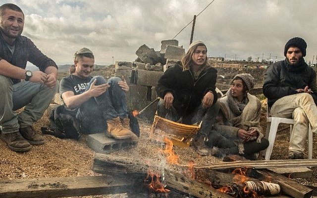 Young Israeli settlers gather around a fire in the settlement outpost of Amona, which was established in 1997 and built on private Palestinian land, in the West Bank on December 18, 2016. (AFP PHOTO / JACK GUEZ)