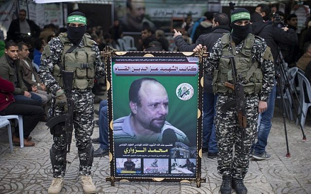 Members of the Ezzedine al-Qassam Brigades, the military wing of Hamas, hold a banner bearing a portrait of one of their leaders, Mohamed Zoari, who was killed in Tunisia, during a ceremony in his memory on December 18, 2016, in Gaza City. (AFP PHOTO / MAHMUD HAMS)